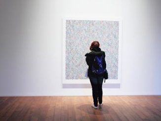 Chica mirando un cuadro en un museo