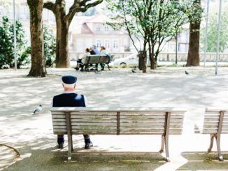 Un hombre sentado en el banco de un parque