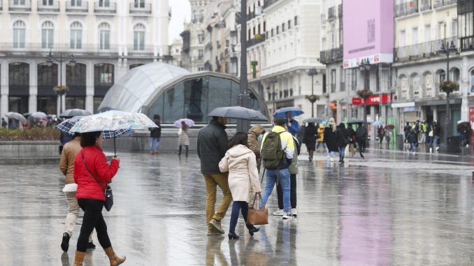 Varias personas se protegen de la lluvia con paraguas en la Puerta del Sol, en una fotografía de archivo. EFE/Víctor Casado
