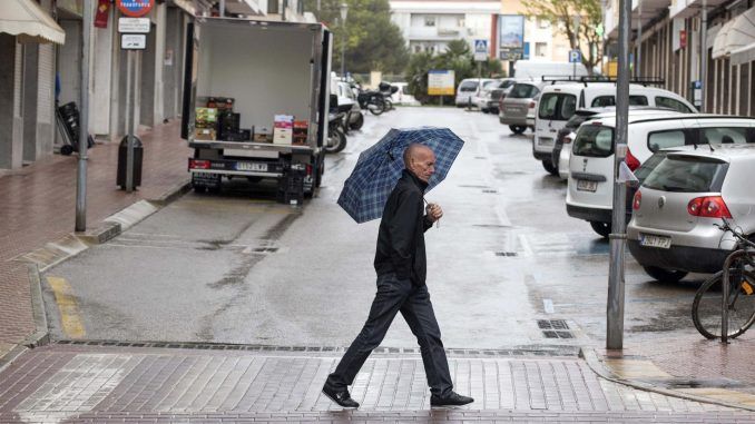 Un hombre pasea bajo la lluvia por las calles de Mahón, Menorca este jueves. La entrada, en la segunda mitad del día, de un frente atlántico con una masa de aire frío del norte traerá descenso de temperaturas y precipitaciones que afectarán al Cantábrico, donde pueden ser localmente persistentes, y se moverán del noroeste hacia sudeste afectando además a Galicia, zonas de la Meseta, Andalucía y nordeste peninsular, según informa la Aemet. EFE/ David Arquimbau Sintes
