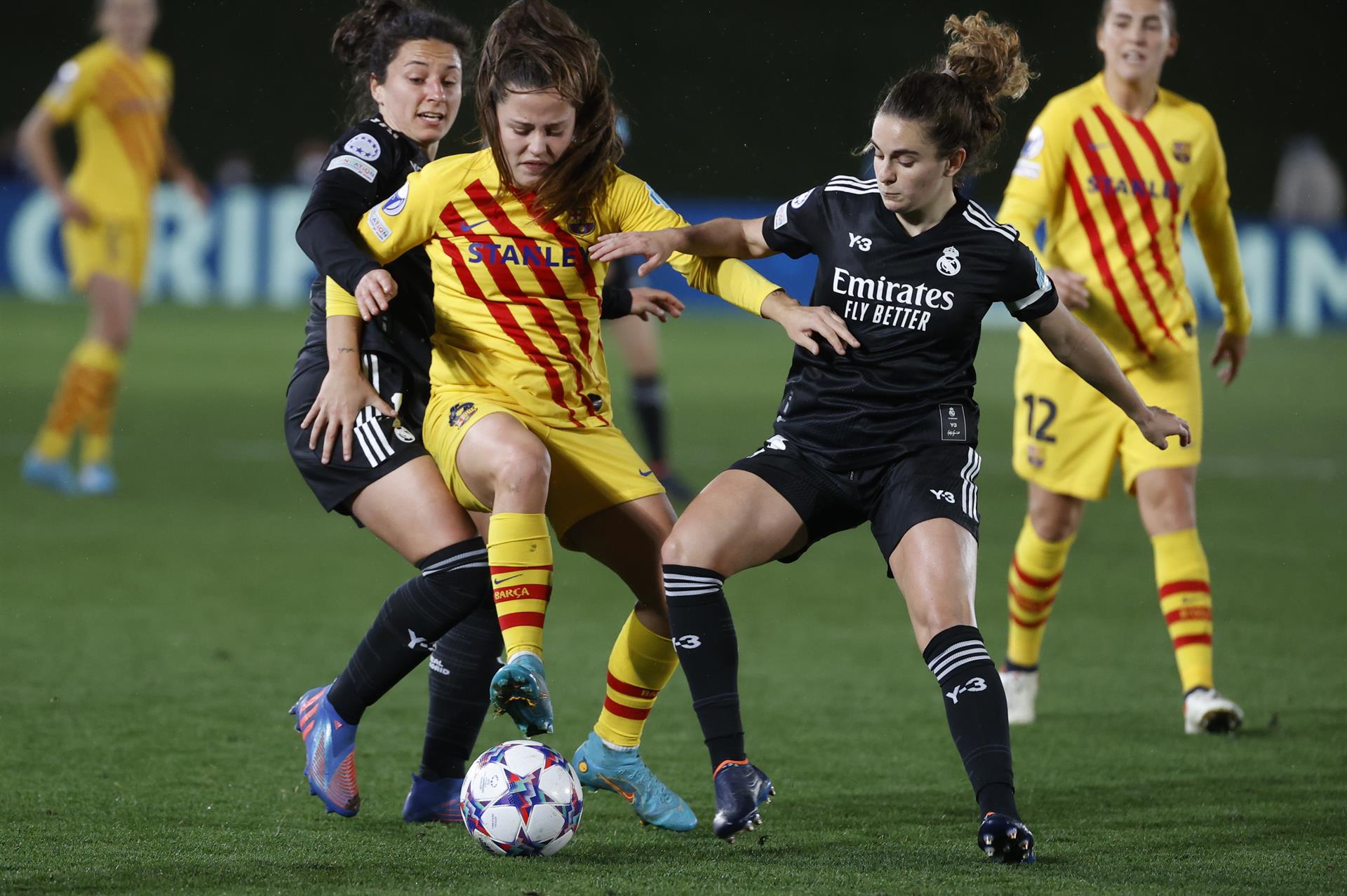 La defensa alemana del Real Madrid Babbett Peter (d) disputa el balón ante Claudia Pina (c), delantera del Barcelona, durante el encuentro de cuartos de final de Liga de Campeones femenina entre el Real Madrid y el FC Barcelona, en el estadio Alfredo Di Stéfano en Madrid. EFE/ Juanjo Martín
