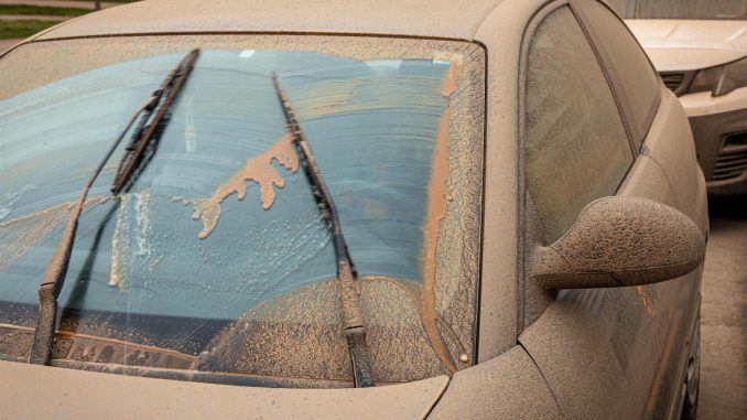 Un conductor trata de limpiar los cristales de su automóvil del polvo en suspensión que proviene del Sáhara que tras la lluvia acaecida en Logroño este martes ha teñido la ciudad de un color naranja. EFE/ Raquel Manzanares
