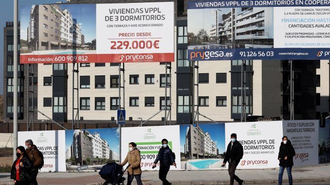 Varios viandantes pasan ante una promoción de viviendas en construcción, en una fotografía de archivo. EFE/Chema Moya
