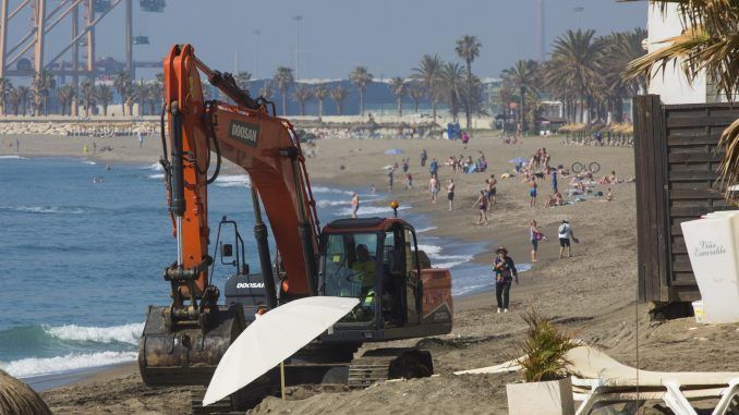 Una máquina trabaja para regenerar la arena de la playa de la Malagueta en Málaga. EFE/Álvaro Cabrera
