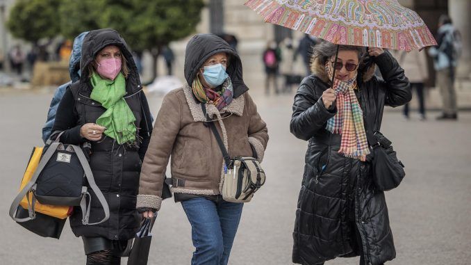 Varias personas pasean bien abrigadas y con paraguas por el centro de la ciudad de Valencia. EFE/Biel Aliño
