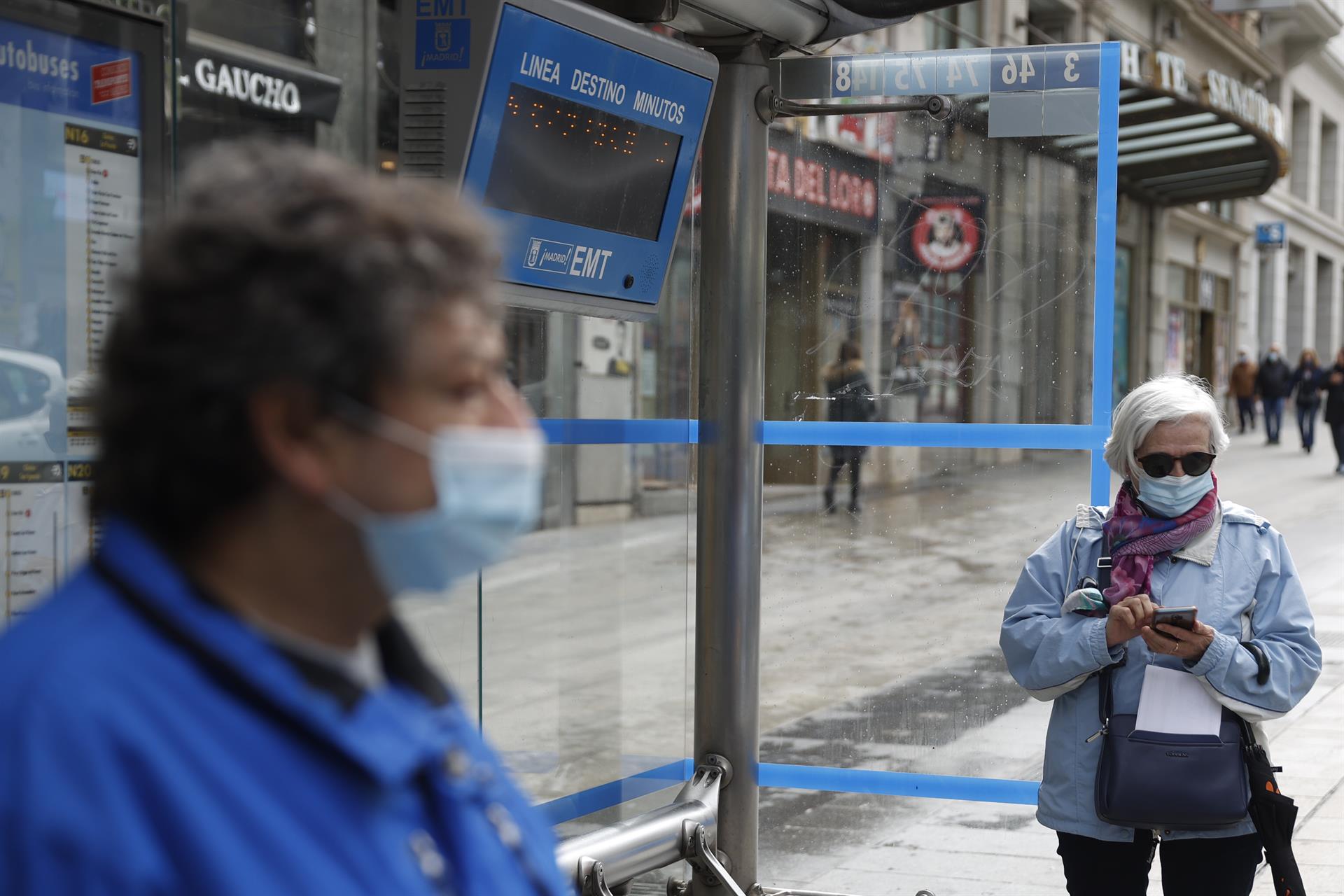 Una mujer espera en la parada la llegada de un autobús de línea en la Gran Vía de Madrid, este miércoles. El Boletín Oficial del Estado (BOE) publica este miércoles el real decreto por el que se elimina en España definitivamente la obligatoriedad de llevar mascarillas en interiores, salvo en el transporte público, centros sanitarios, residencias y farmacias. EFE/Mariscal
