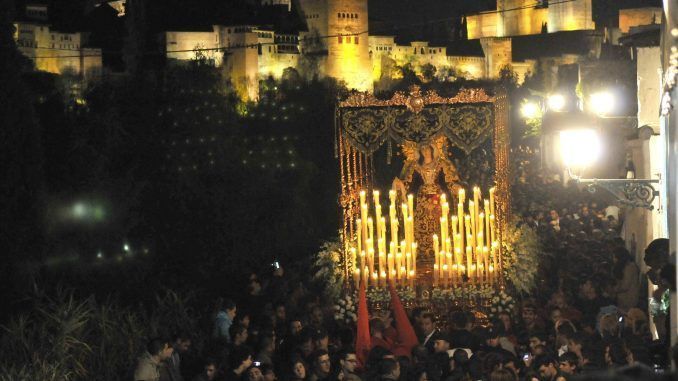 Una cofradía durante su recorrido por las calles de Granada pasa por delante de la Alhambra. EFE/Archivo
