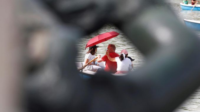 Una familia se protege del sol mientras dan un paseo en barca en el lago del Parque del Retiro de Madrid, en una imagen de archivo. EFE/J.J. Guillén
