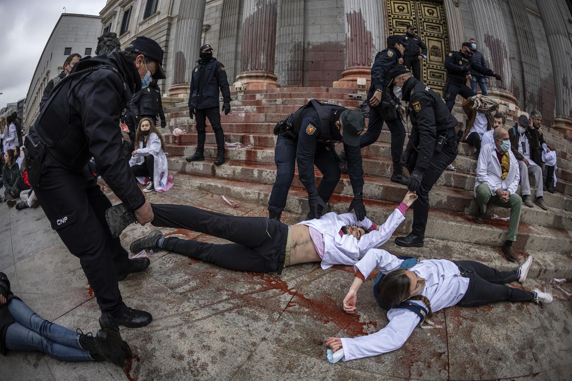 Varios policías retiran a los manifestantes del grupo Scientist Rebellion de la Puerta de los Leones tras arrojar pintura contra la fachada del Congreso de los Diputados durante una protesta en Madrid, este miércoles. EFE/Rodrigo Jiménez
