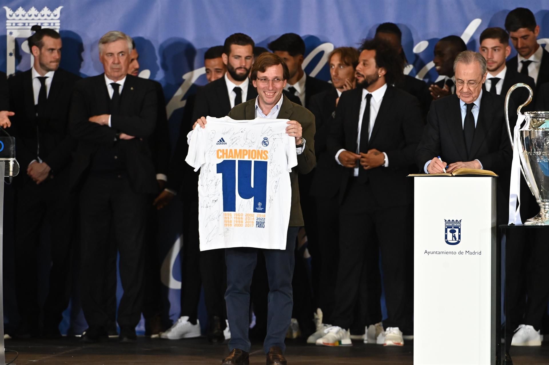 El alcalde de Madrid, José Luis Rodríguez Almeida, muestra la camiseta del Real Madrid que le ha entregado el capitán del equipo, Marcelo Vieira (2d), en presencia del presidente de la entidad, Florentino Pérez (d), este domingo en el Ayuntamiento de Madrid, una de las paradas del recorrido realizado esta tarde por el equipo para celebrar su victoria en la final de la Liga de Campeones. EFE/Fernando Villar
