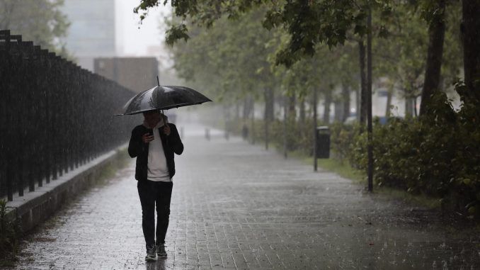 Fotografía de archivo de un hombre pasea bajo la lluvia en Valencia. EFE/Ana Escobar
