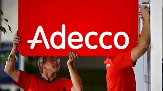 Dos trabajadores que instalan un cartel con el logo de la empresa de contratación temporal Adecco, en una fotografía de archivo. EFE/Laurent Gillieron
