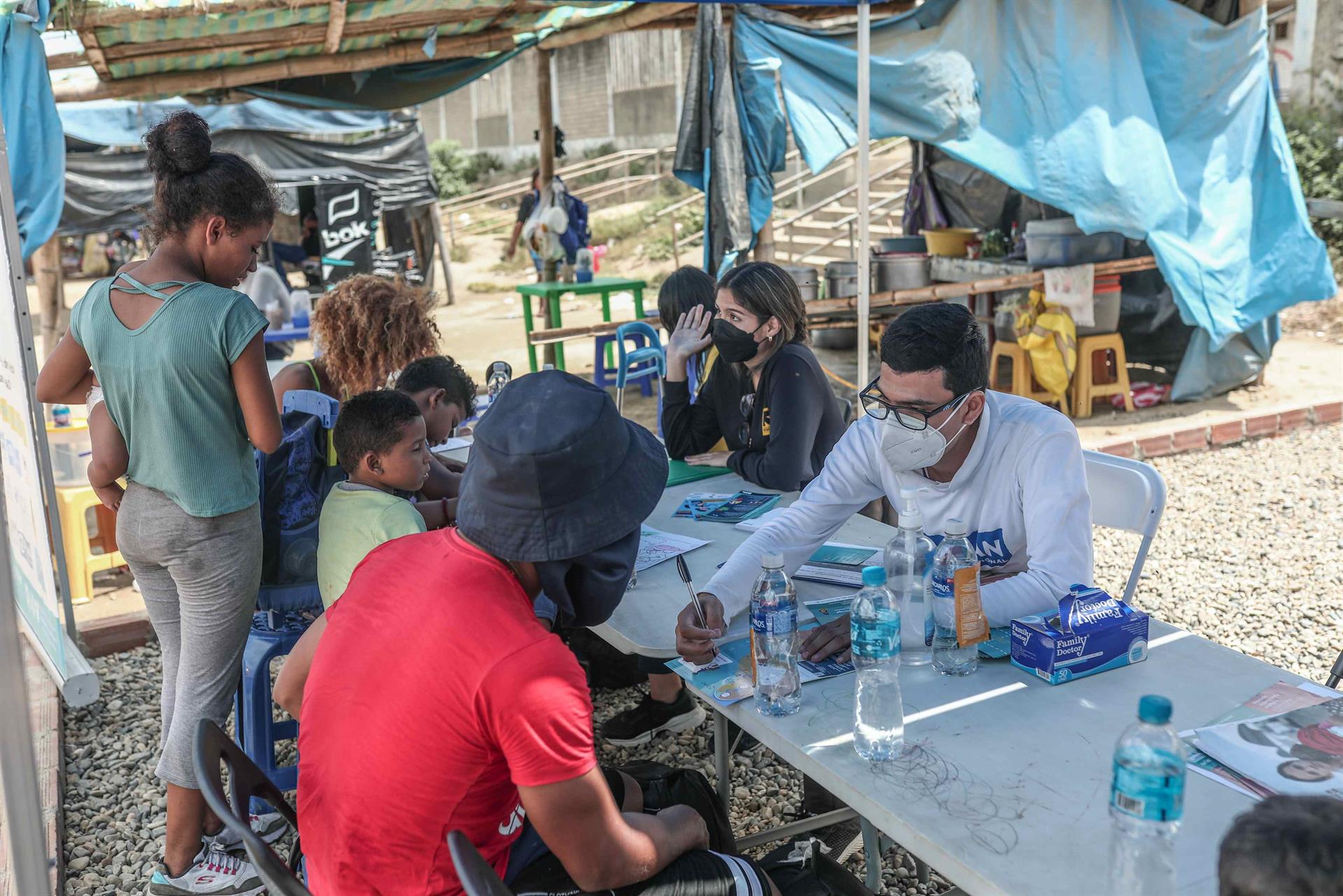 Un trabajador de la Agencia de la ONU para los refugiados (Acnur) brinda información a migrantes venezolanos en la localidad de Aguas Verdes en Túmbes (Perú). EFE/ Aldair Mejía
