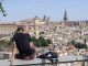 Un chico descansa bajo el sol con la ciudad de Toledo de fondo este jueves. EFE/Ismael Herrero