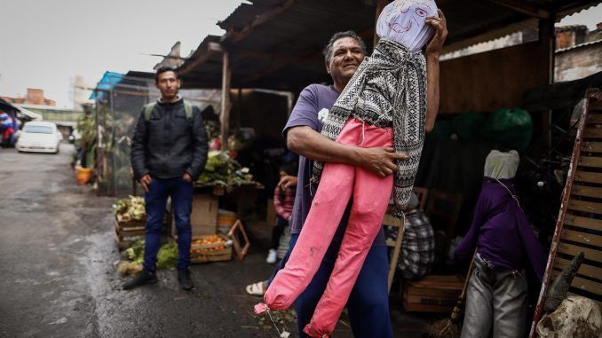 Un vendedor baila con un Judas Kai, muñeco de trapo el cual es quemado en la noche de la fiesta de San Juan, hoy, en el Mercado 4 en Asunción (Paraguay). EFE/ Nathalia Aguilar
