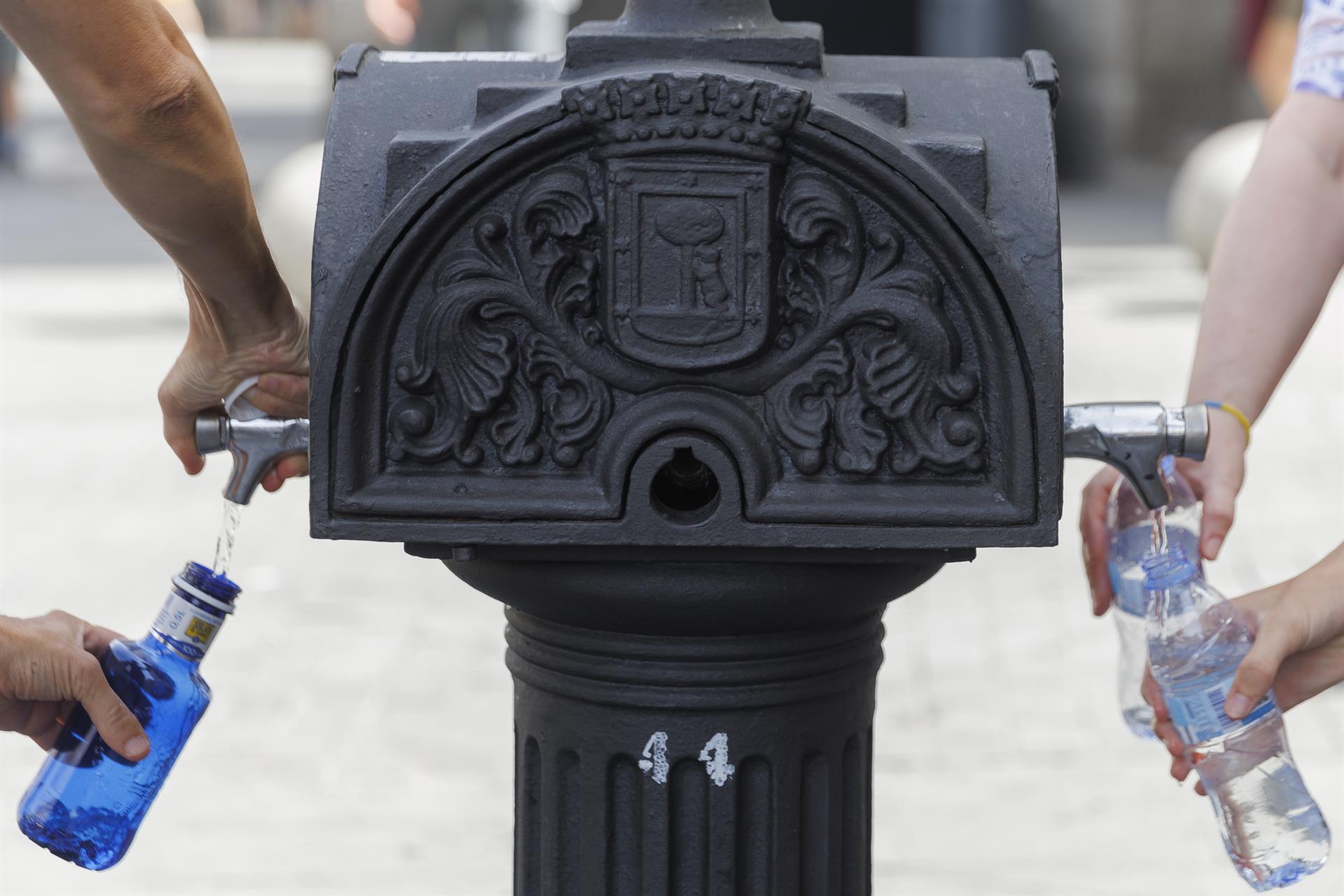 Unos turistas llenan sus botellas de agua este lunes en una fuente de Madrid. EFE/ Sergio Pérez
