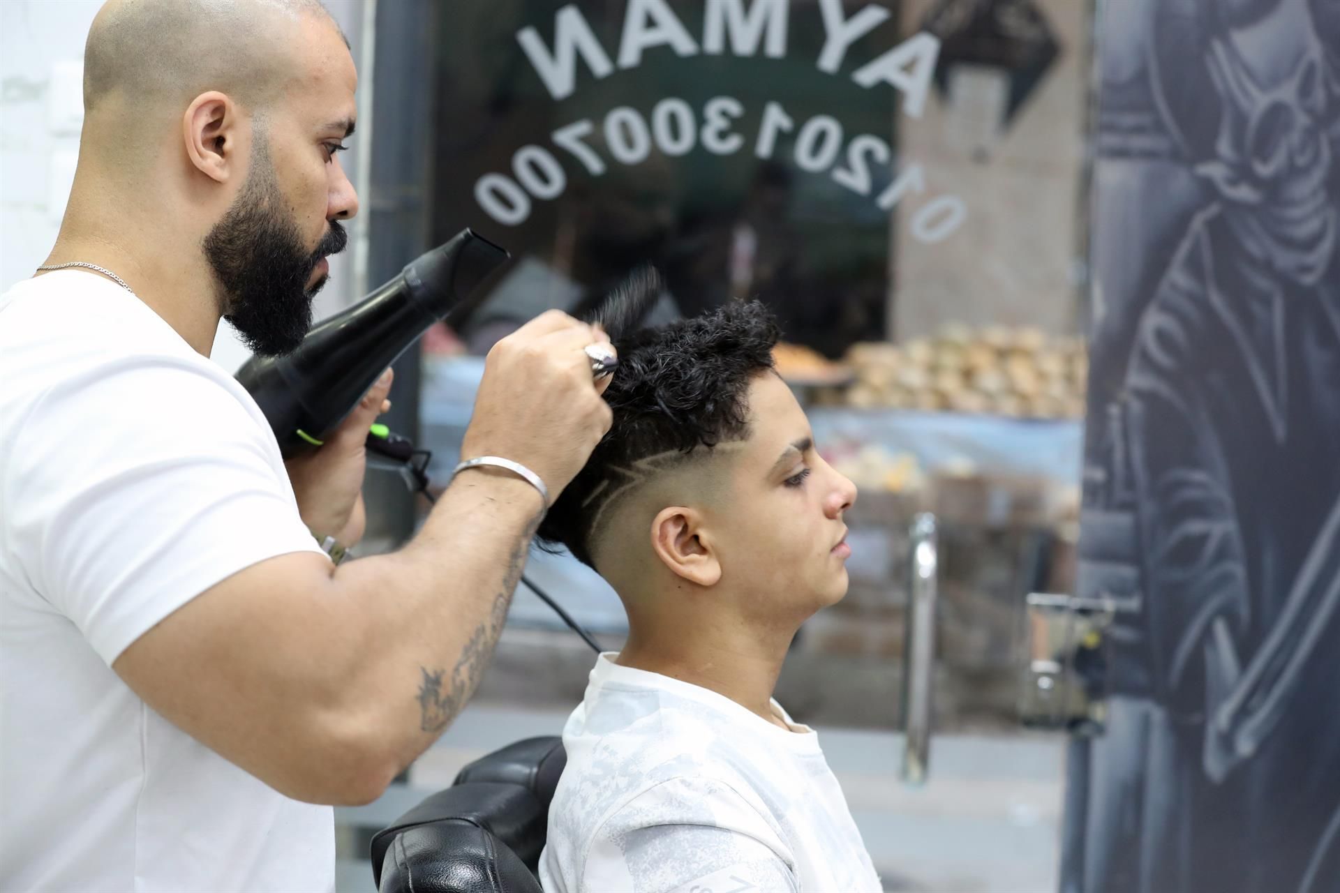 Ayman corte el pelo de un chico en una peluquería del popular barrio de Ain Shams, en el este de El Cairo. EFE/EPA/KHALED ELFIQI
