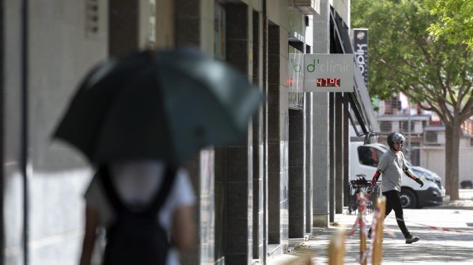 Una joven camina por una calle de Lleida, bajo un termómetro que indica los 47ºC. EFE/ Ramon Gabriel
