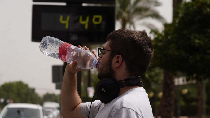 Un joven bebe agua junto a un termómetro de calle que marca 44º en el centro de Córdoba. EFE/Archivo
