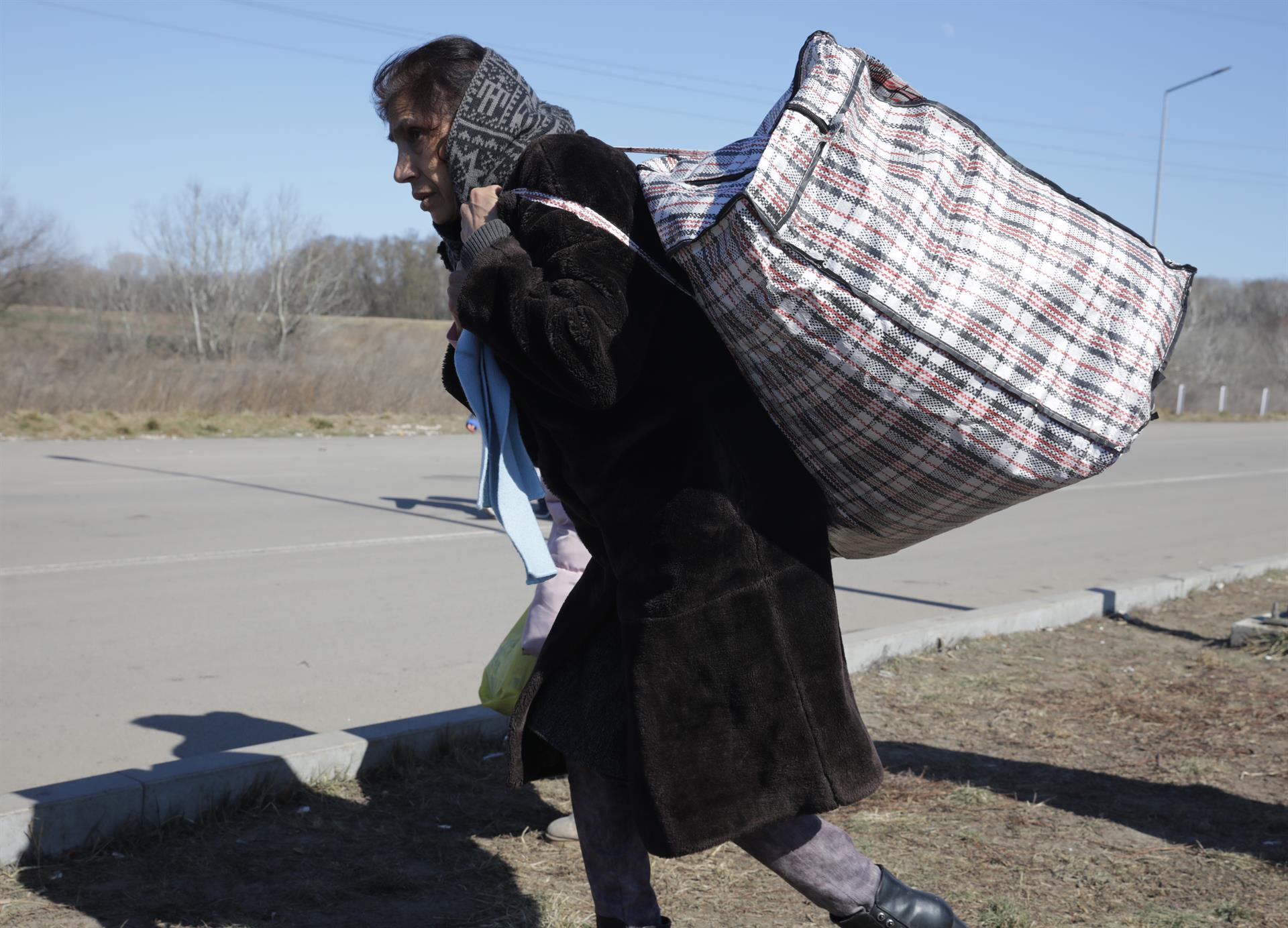 Una mujer ucraniana caminaba con sus pertenencias en la frontera entre Uracrania y Moldavia, en la localidad de Palanca, tras huir de su país el pasado mes de marzo. EFE/EPA/AMEL PAIN
