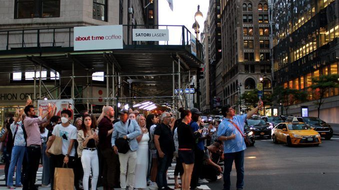 Un grupo de personas toman fotografías a la puesta del sol entre edificios hoy, en una calle de Manhattan en Nueva York (EE.UU.). EFE/ Sarah Yáñez-Richards
