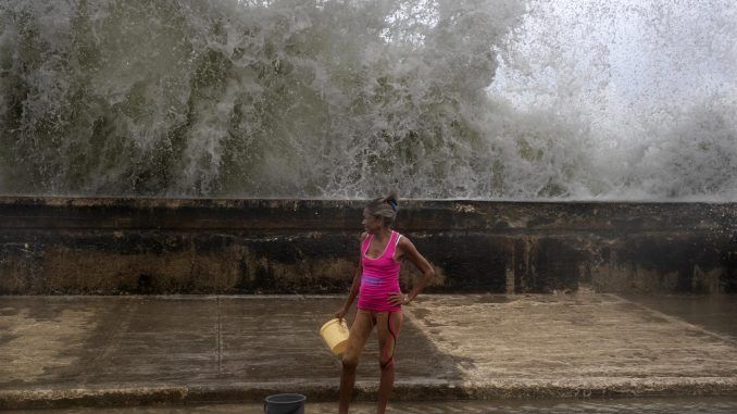 Una mujer posa mientras recoge agua de mar para limpiar su casa, hoy, en el malecón de La Habana (Cuba). EFE/ Yander Zamora
