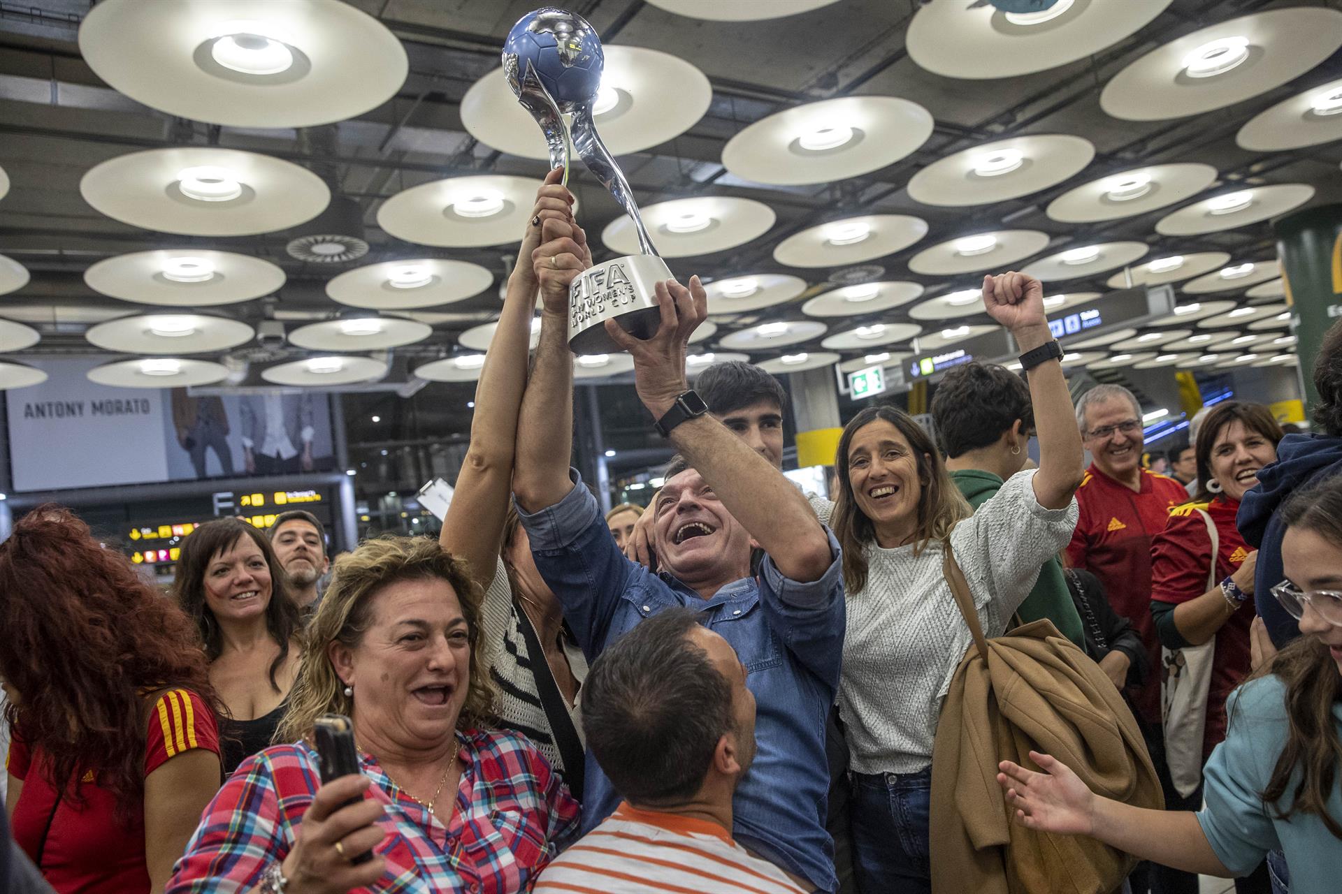 Las jugadoras de la selección española sub17 y sus familias levantan la copa a su llegada al aeropuerto Adolfo Suárez Madrid-Barajas este lunes, tras proclamarse campeonas del mundo ayer en India. La selección española femenina logró su segundo Mundial sub-17 consecutivo tras vencer en la final a la selección de Colombia el pasado domingo. EFE/ Daniel González
