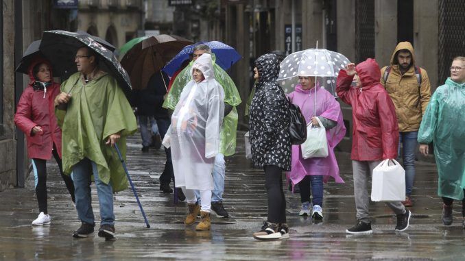 Turistas y peregrinos se protegen de la lluvia en Santiago de Compostela, este jueves. EFE/ Xoán Rey
