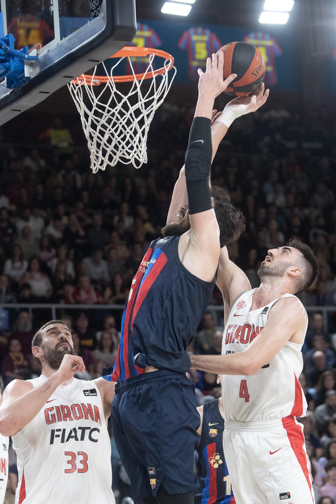 El pívot turco del Barcelona Sertac Sanli (c) hace un mate defendido por Eric Vila (d) y Marc Gasol, alero y pívot del Girona, durante el partido de la Liga Endesa de baloncesto entre el FC Barcelona y el Bàsquet Girona disputado este domingo en el Palau Blaugrana de Barcelona. EFE/ Marta Pérez
