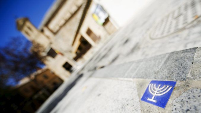 Azulejos como este, que representa la Menorah, indican al visitante que se encuentra en la judería de Toledo. Al fondo, la Sinagoga del Transito. EFE/Ismael Herrero
