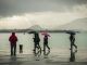 Gente pasea bajo la lluvia junto a la bahía de Santander este viernes donde se han registrado lluvias y descenso de temperaturas. EFE/ Román G. Aguilera