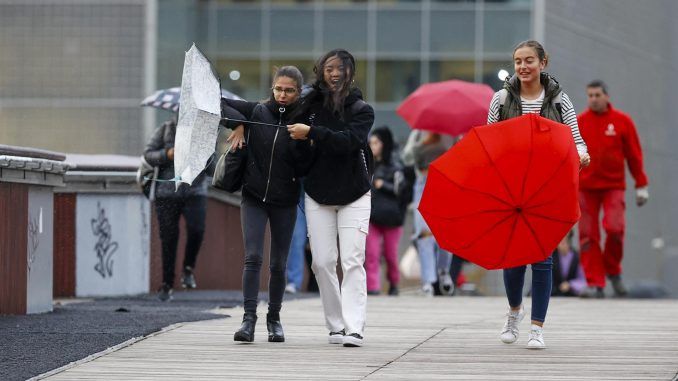 Mujeres sujetan sus paraguas por el fuerte viento ayer martes en Bilbao. EFE/Luis Tejido