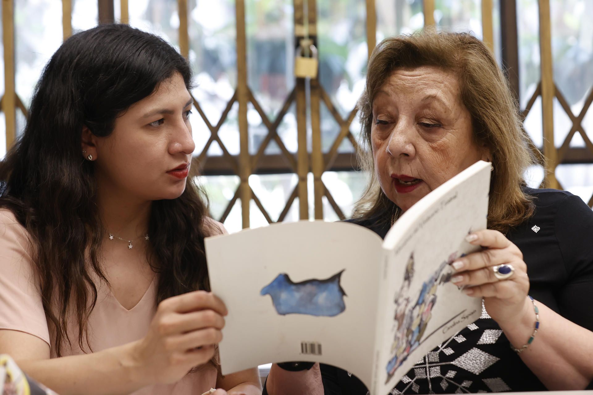 Vitoria Quiroz (d) y María José Zapata (i) participan en un club de lectura, el 30 de noviembre 2022, en la llamada Biblioteca de las Mujeres, en Santiago (Chile). EFE/ Elvis González
