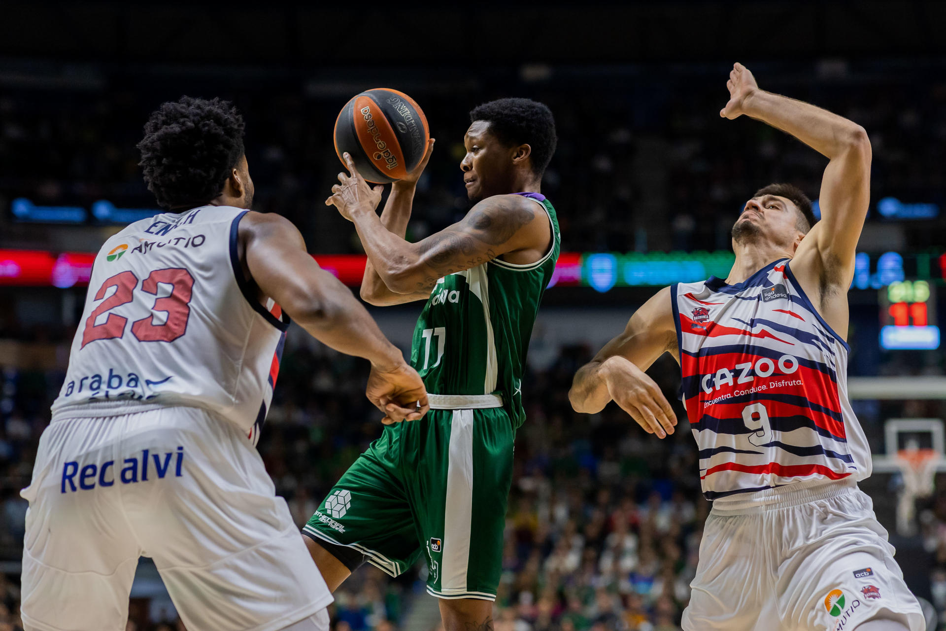 El base estadounidense del Unicaja, Tyson Carter (c) es defendido por el escolta serbio del Cazoo Baskonia, Vanja Marinkovic(d) y el pívot estadounidense del Cazoo Baskonia, Steven Enoch (i) durante la vigésima jornada de la Liga Endesa disputado esta noche en el Palacio de los Deportes José María Martín Carpena. EFE/Carlos Díaz
