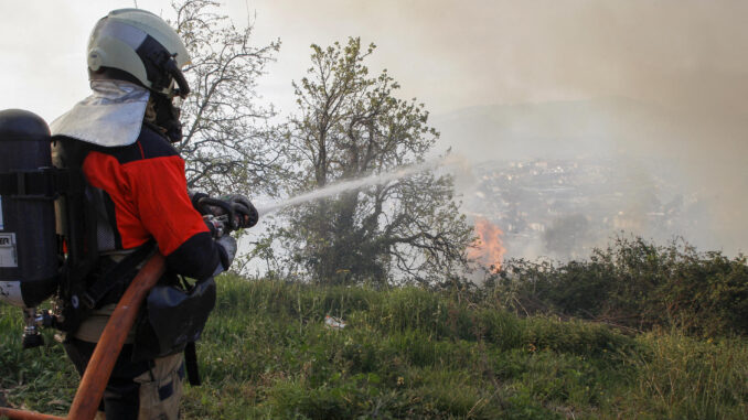 Un bombero intenta sofocar las llamas en el Monte Naranco, junto a la ciudad de Oviedo, este viernes. EFE/Juan González
