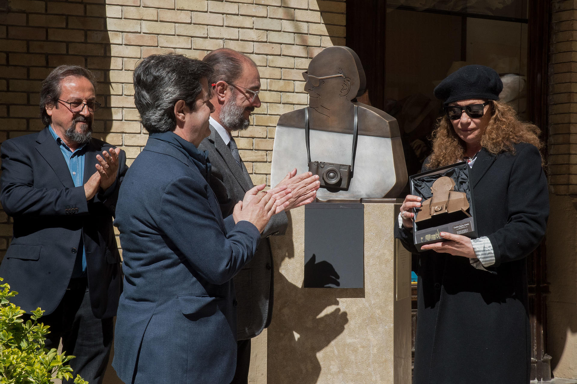 El presidente de Aragón, Javier Lambán (3i), junto a la viuda de Carlos Saura, Eulalia Ramón (d), el alcalde de Huesca Luis Felipe Serrate​ (2i) y el escultor Julio Luzán (i) durante el acto de entrega de una escultura del busto de Carlos Saura a la ciudad de Huesca, lugar donde nació, por parte del Gobierno de Aragón. EFE/ Javier Blasco
