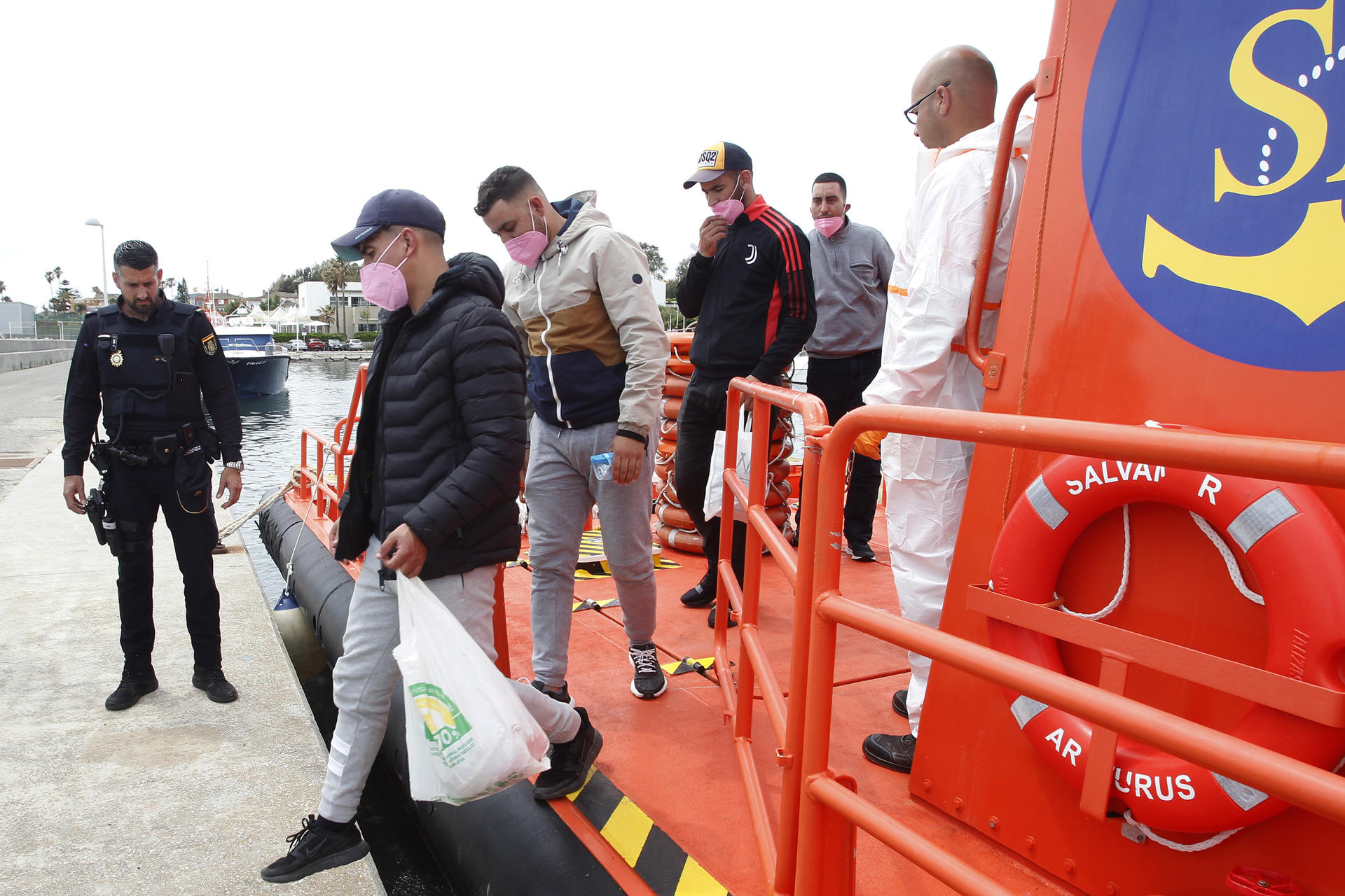 La embarcación de Salvamento Marítimo ha llegado al puerto de Algeciras (Cádiz) con cuatro varones de origen marroquí que han sido rescatados en aguas del estrecho. En la foto, los rescatados bajan a puerto para ser trasladados por la policía nacional. EFE/A.Carrasco Ragel
