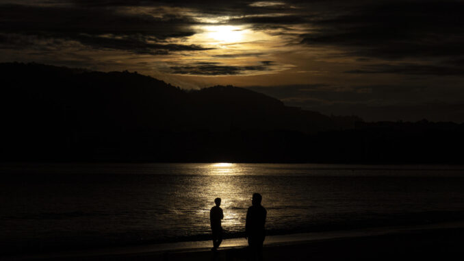 Varias personas observan el amanecer este miércoles en la playa de Ondarreta de San Sebastián. EFE/Javier Etxezarreta
