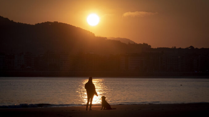 Una joven observa el amanecer este lunes en la playa de Ondarreta de San Sebastián. EFE/Javier Etxezarreta
