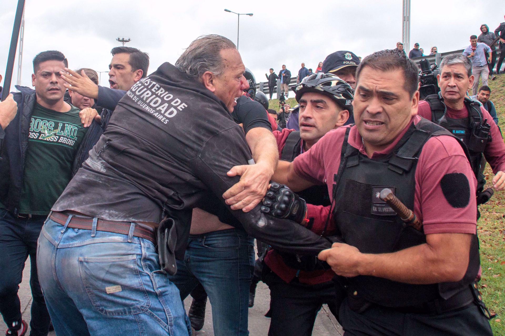 El ministro de Seguridad provincial, Sergio Berni (2i-espaldas), corre escoltado por varios agentes luego de resultar herido durante una protesta, hoy, en La Matanza, provincia de Buenos Aires (Argentina). EFE/ Str
