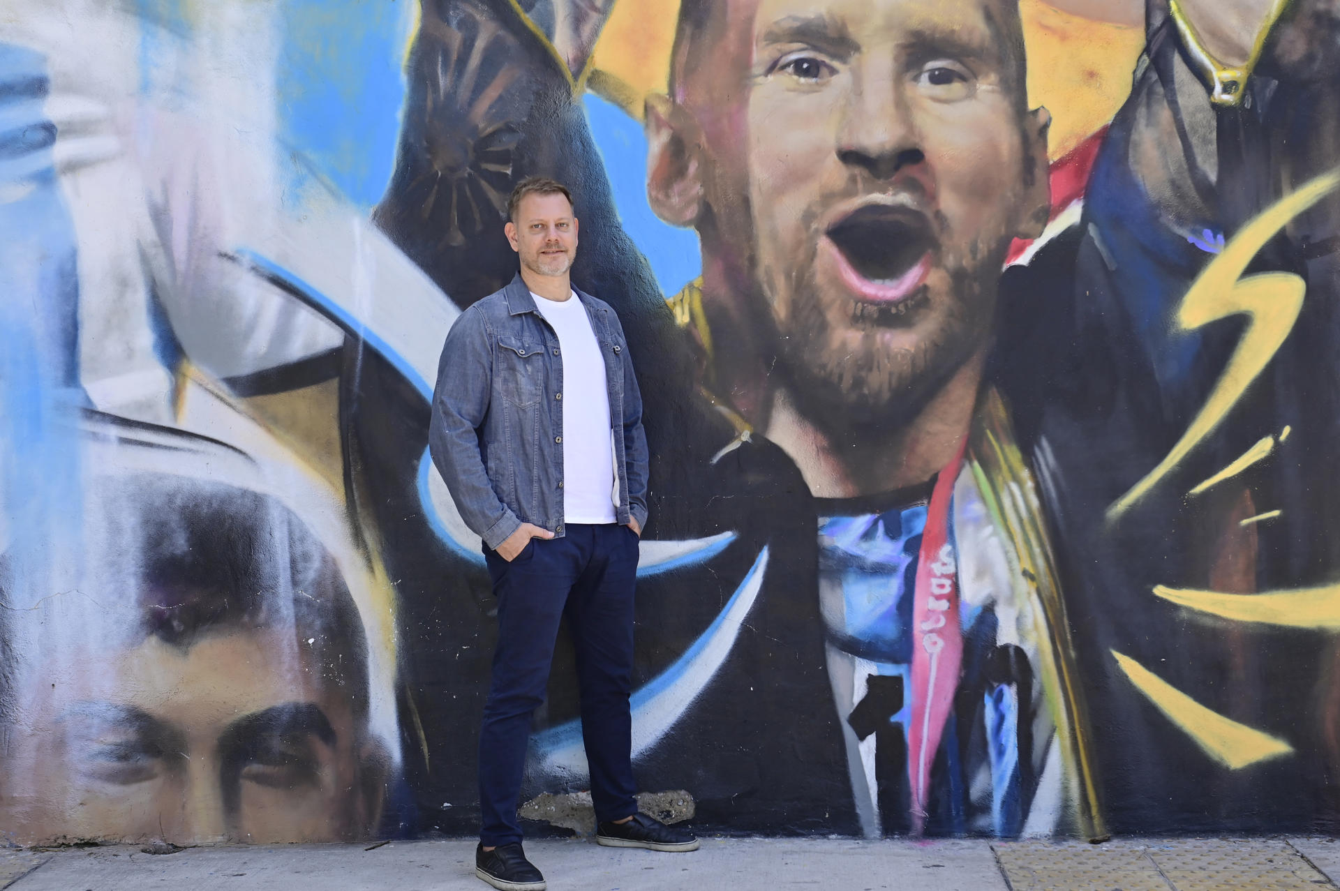 El periodista Sebastián Fest posa durante una entrevista con EFE junto a una pintura de Lionel Messi en Buenos Aires (Argentina).  EFE/ Marías Martín Campaya
