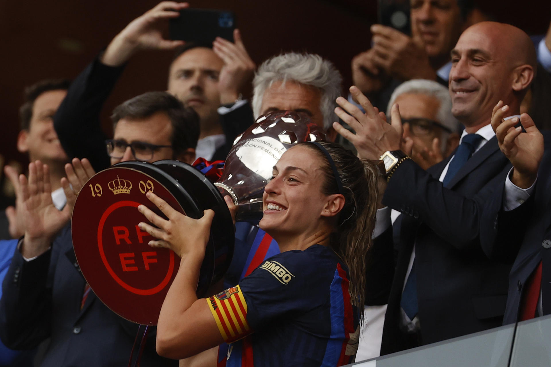 La capitana del Barcelona Alexia Putellas (c) levanta la copa de campeonas de Liga F, frente a Luis Rubiales (d), presidente de la RFEF tras finalizar la jornada 27 de la Liga F que Barcelona y Sporting de Huelva disputan este domingo en el Estadi Johan Cruyff de la Ciudad Condal. EFE/ Toni Albir
