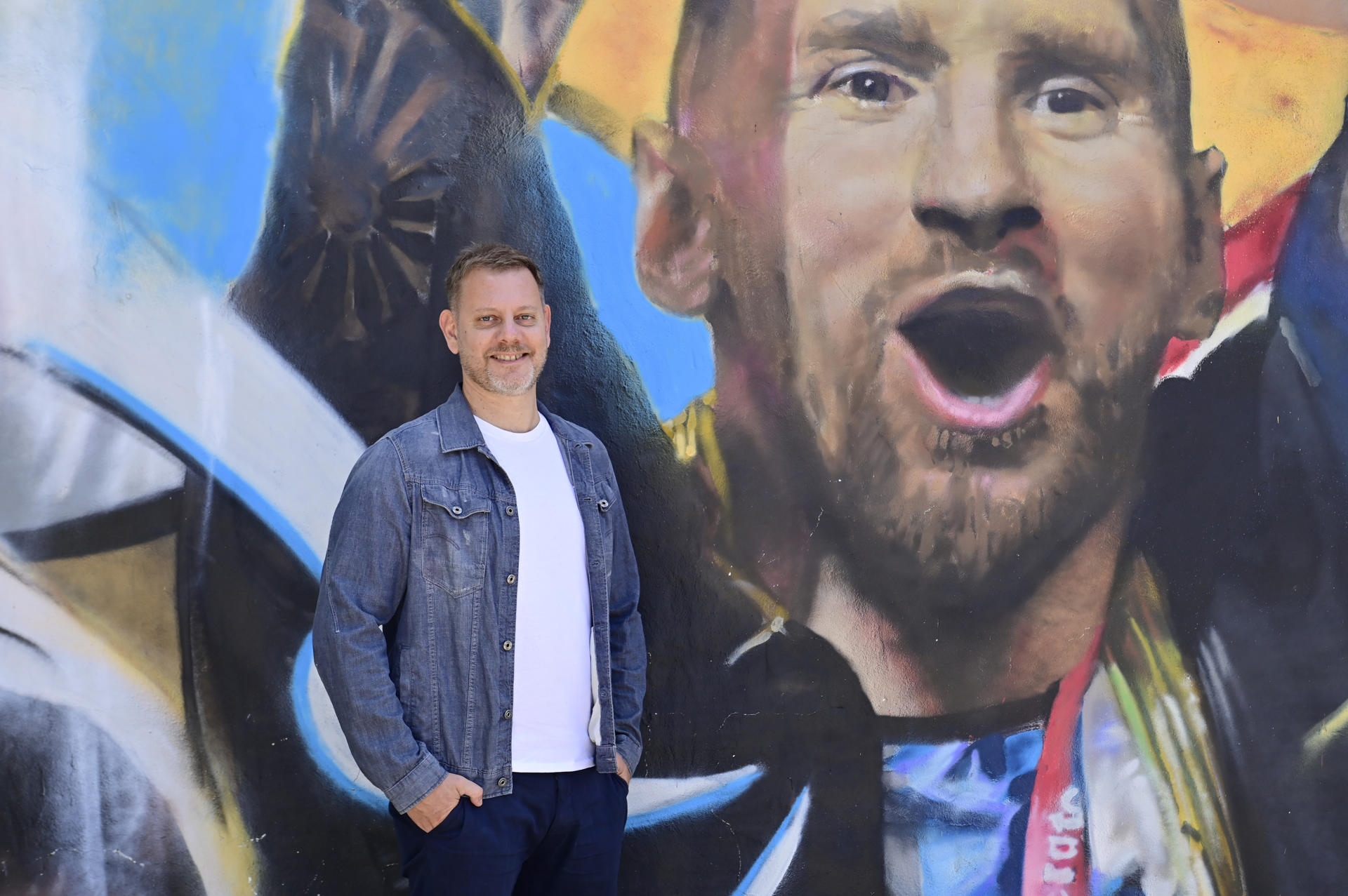 El periodista Sebastián Fest posa durante una entrevista con EFE junto a una pintura de Lionel Messi en Buenos Aires (Argentina).  EFE/ Marías Martín Campaya
