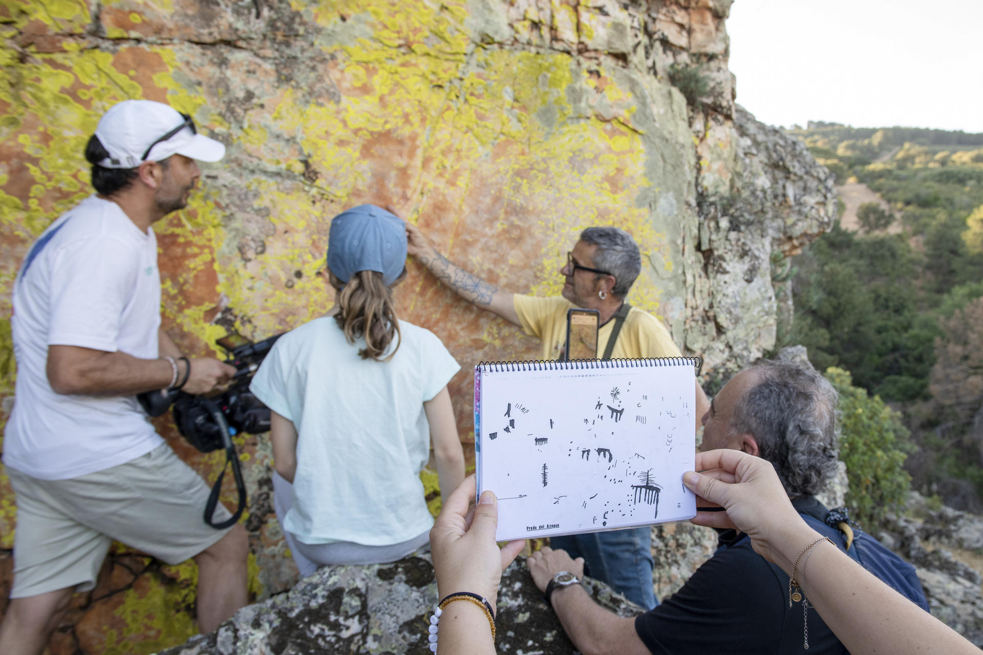 Una visitante localiza con un esquema con dibujos las pinturas rupestres en la roca en las pinturas rupestre de Prado del Azogue. La UNESCO declaró en 1998 como Patrimonio de la Humanidad el arte rupestre levantino del Arco Mediterráneo Español. EFE/José Manuel Pedrosa.
