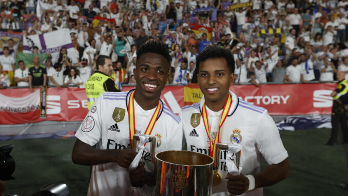 Los atacantes brasileños del Real Madrid Vinícius Júnior (i) y Rodrygo Goes posan con la Copa de S.M. El Rey entregada por Felipe VI tras vencer 2-1 a Osasuna en la final de la Copa del Rey de fútbol este sábado en el estadio de La Cartuja de Sevilla. EFE/ Julio Munoz
