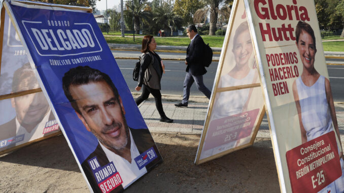 Fotografía de archivo de personas que caminan frente a carteles de propaganda electoral para consejeros Constitucionales en Santiago (Chile). EFE/Elvis González
