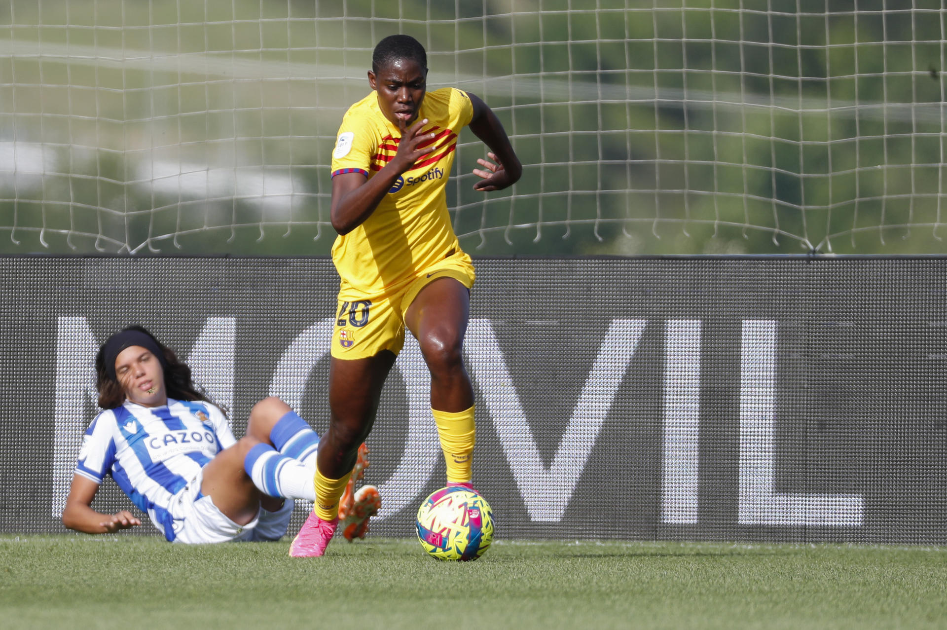 La delantera del FC Barcelona Asisat Oshoala (d) escapa de Andreia Jacinto, de la Real Sociedad, durante el partido de la Liga F de fútbol disputado este sábado en San Sebastián. EFE/Juan Herrero
