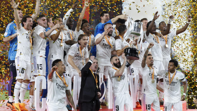 El capitán del Real Madrid, Karim Benzema (c-abajo) levanta junto a sus compañeros y al técnico italiano Carlo Ancelotti (2i-abajo), la Copa de S.M. El Rey entregada por Felipe VI tras vencer 2-1 a Osasuna en la final de la Copa del Rey de fútbol en el estadio de La Cartuja de Sevilla. EFE/ Julio Munoz
