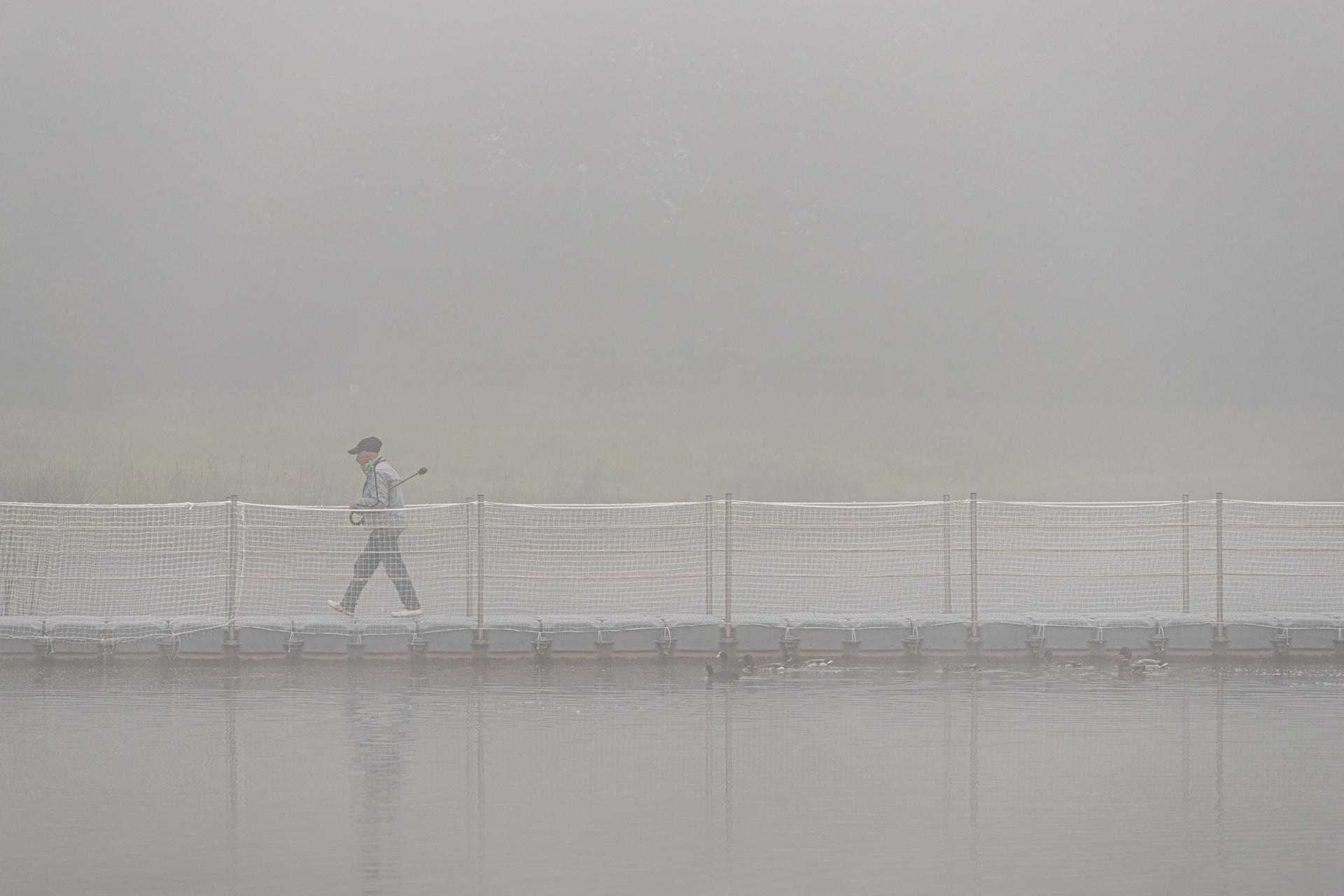 Una mujer pasea en el jardín botánico de Olarizu, en Vitoria, ciudad que amanece este miércoles cubierta por una espesa niebla. EFE/David Aguilar
