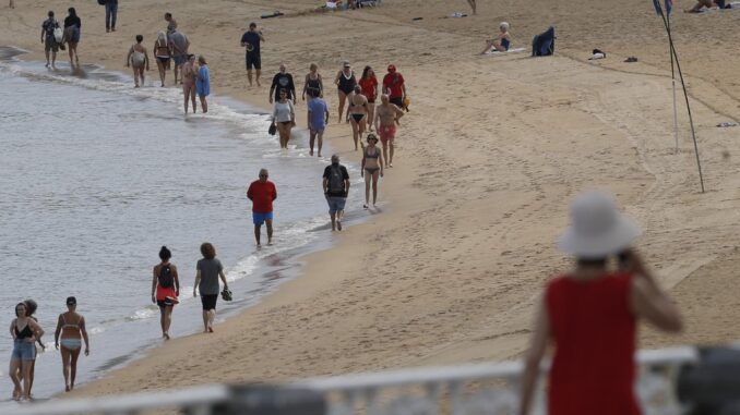 Donostiarras y visitantes pasean este lunes por la playa de la Concha de la capital guipuzcoana. EFE/Juan Herrero
